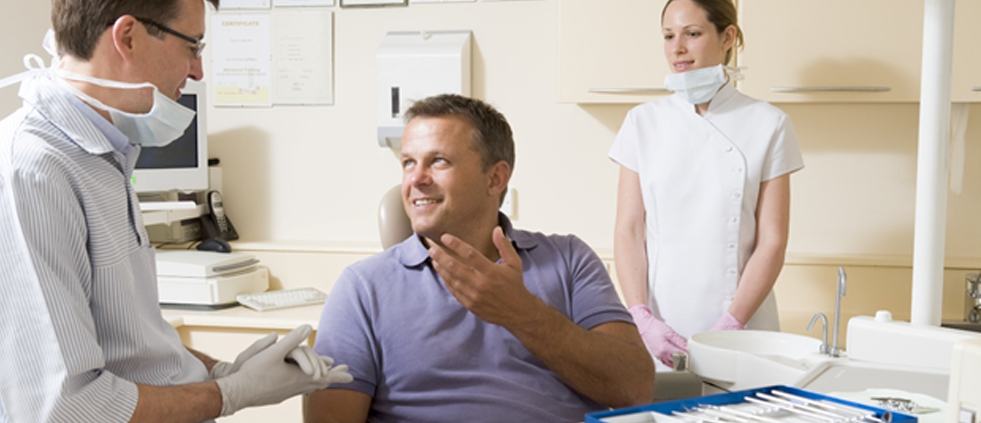 A male dental patient talking to his dentist about dental crowns