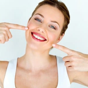 A woman pointing to her healthy smile after tooth colored fillings