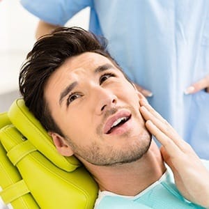 Man in dental chair holding jaw before T M J treatment