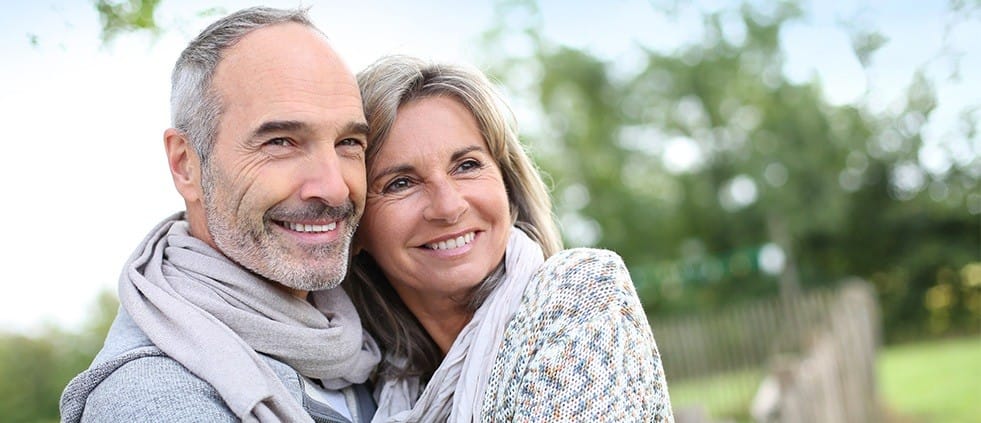 Smiling older man and woman outdoors after restorative dentistry