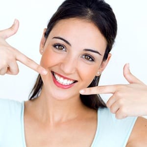 young woman pointing to her smile with straight white teeth