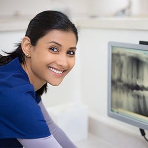 Smiling dental team member looking at dental x-rays