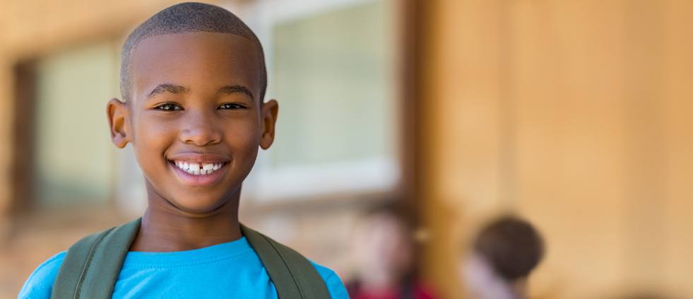 Smiling child with back pack at school