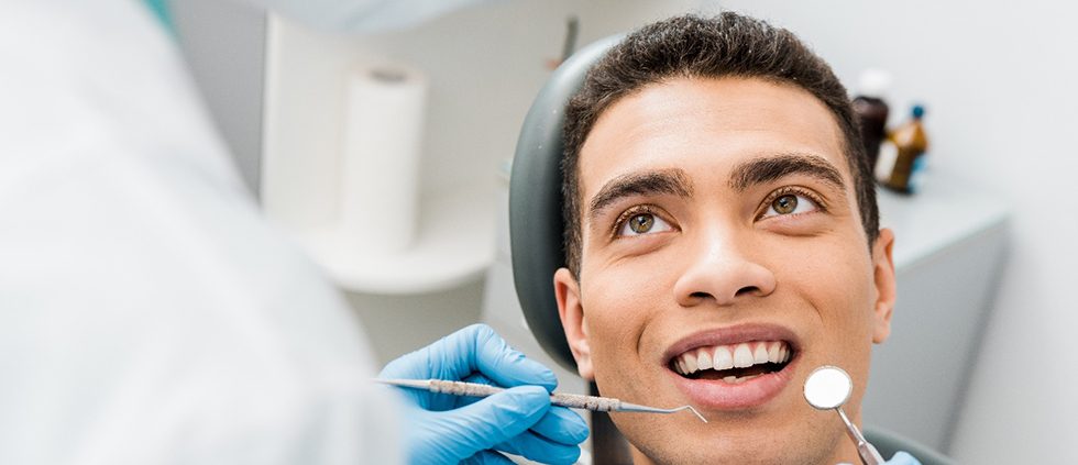 Patient looking up at dentist holding cleaning instruments