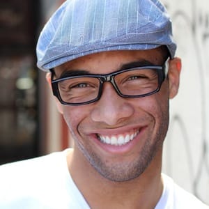 A young man smiling after dental crown placement