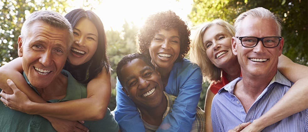 Group of older friends smiling after tooth replacement with dental implants