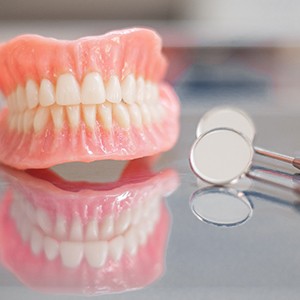 Full set of dentures next to dental mirrors