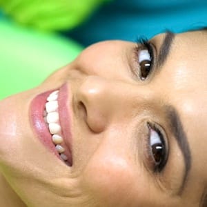 A woman with dental bonding smiling while in the dentist’s chair