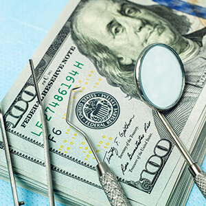 Money and dental tools symbolizing cost of treating dental emergencies