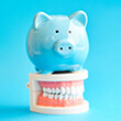 Piggy bank atop model teeth with blue background