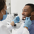 Male dental patient getting dental checkup while smiling
