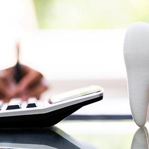 Model tooth and person with calculator figuring out the cost of tooth extraction