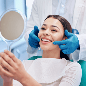 Patient smiling in mirror after successful dental implant salvage