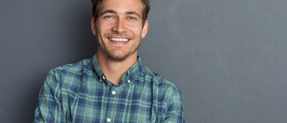 A young man with tooth colored fillings smiling