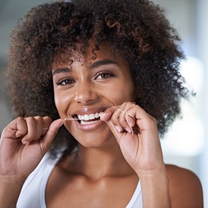 Woman flossing to maintain her dental implants in Lincoln