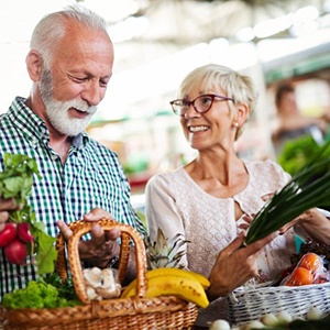 Senior man and woman holding baskets of fruits and vegetables