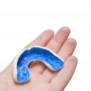 Person holding a blue mouthguard in their hand