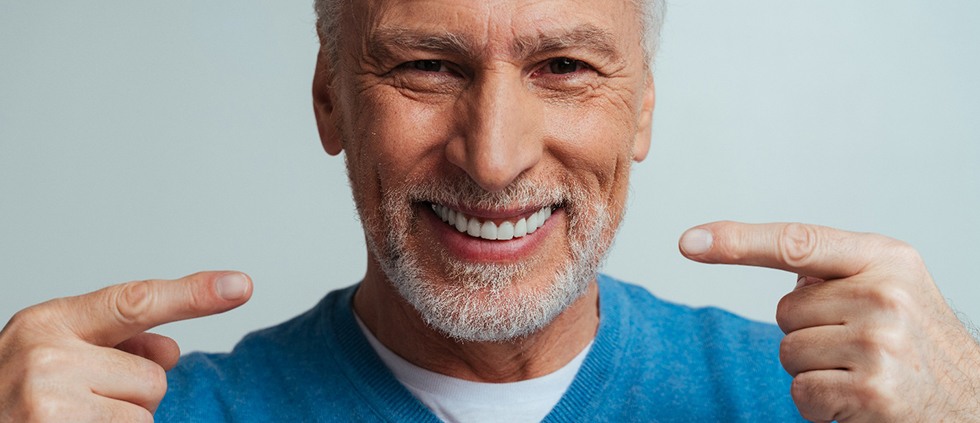 A man pointing to his implant dentures
