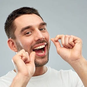 Man flossing to care for dental implants in Lincoln