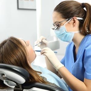 A female patient having her teeth checked by a dentist