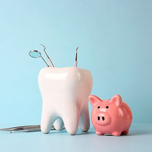 Tooth model and piggy bank against blue background