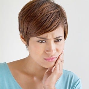 Woman in need of restorative dentistry holding jaw in pain
