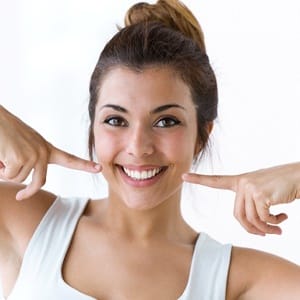 A young woman pointing at her smile after teeth whitening