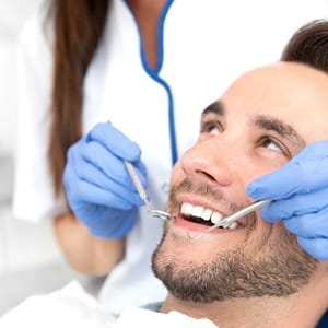 A younger man having his teeth checked at the dentist office