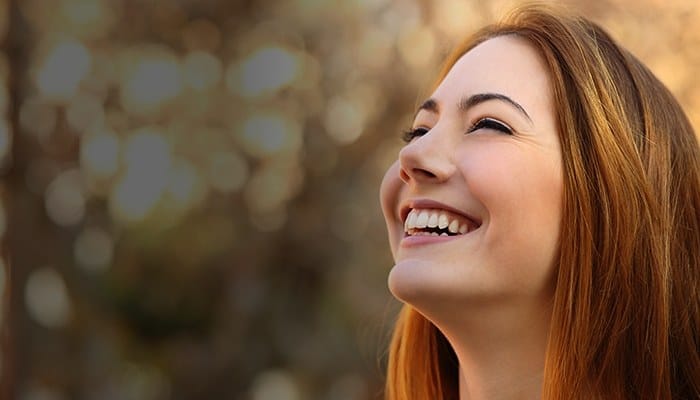 Woman smiling outdoors and looking up