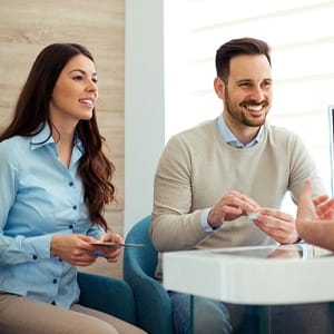 Cosmetic dentist talking to couple in dental office