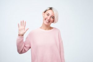 smiling woman waves at Lincoln dentist in COVID-19