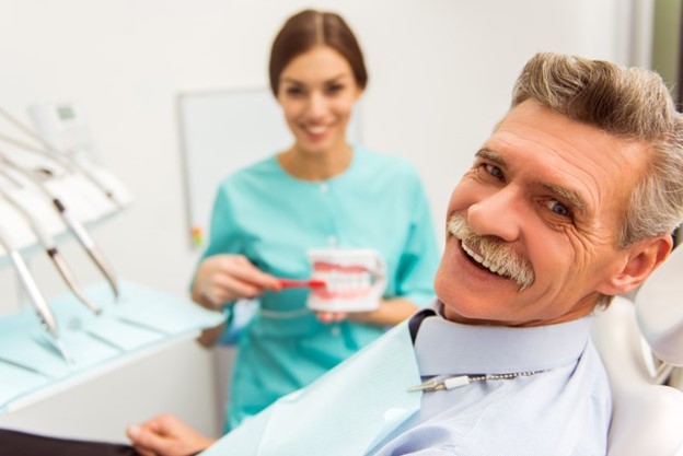 Man at dentist receiving dentures.