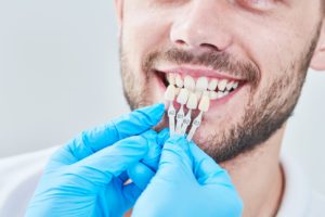 Dental shade guide next to man’s teeth