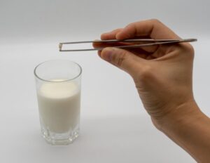 Person putting tooth into glass of milk