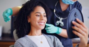 Patient smiling into mirror in dentist's chair.
