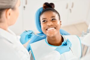 Woman in dental chair smiling at dentist about to examine her mouth
